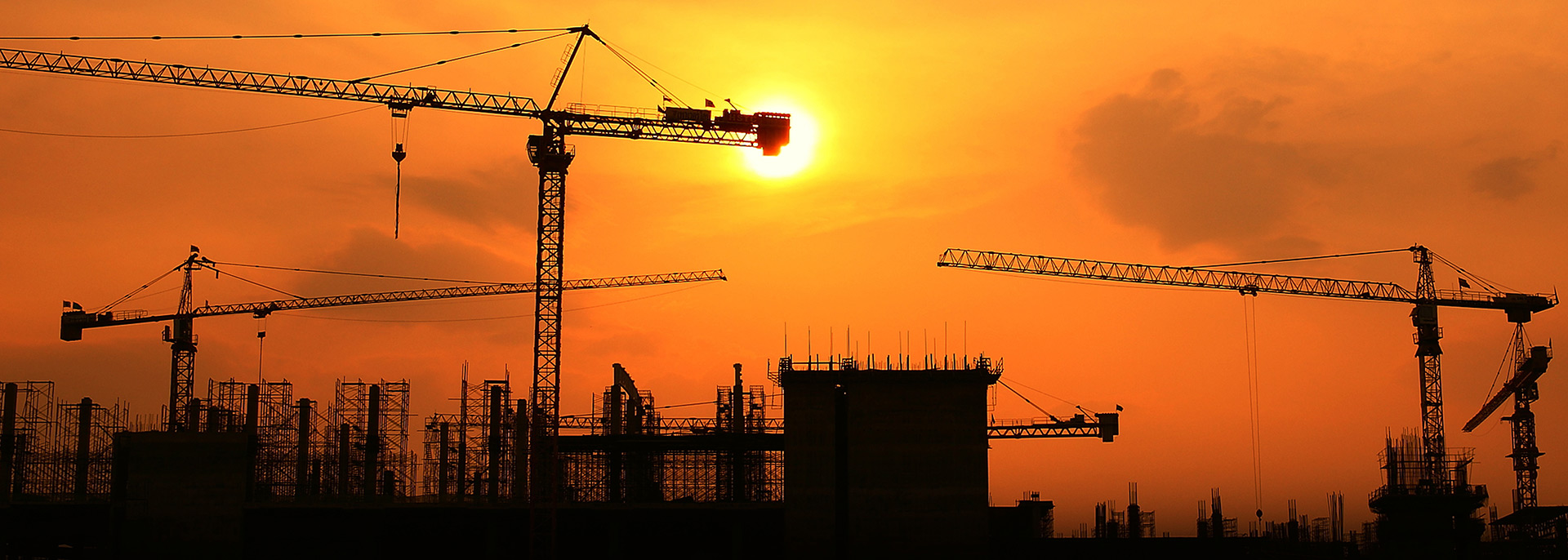 Silhouettes of cranes and construction in a sunset.